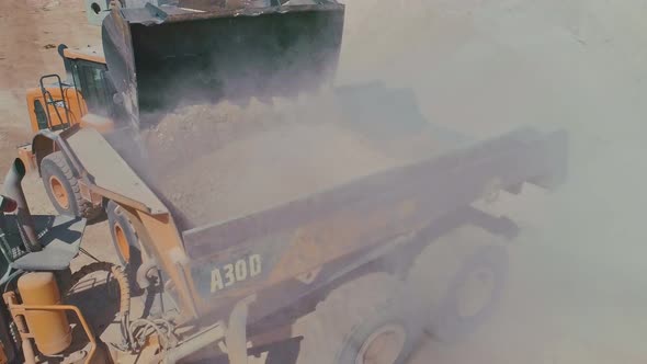 Aerial shot of a large loader loading a truck in a construction site