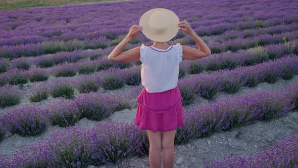 Woman in a Short Purple Dress and a Hat Stands on a Lavender Field