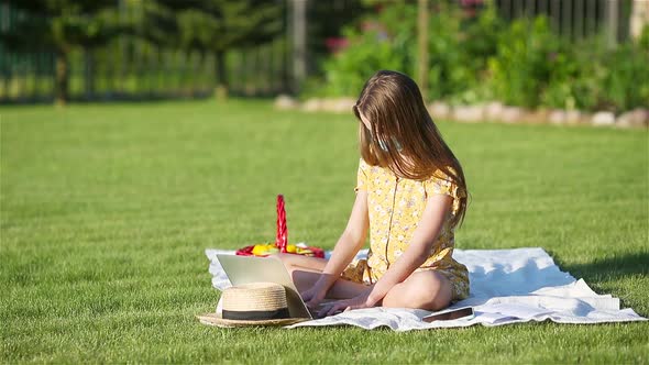 Little Girl Outdoors in the Park with Computer