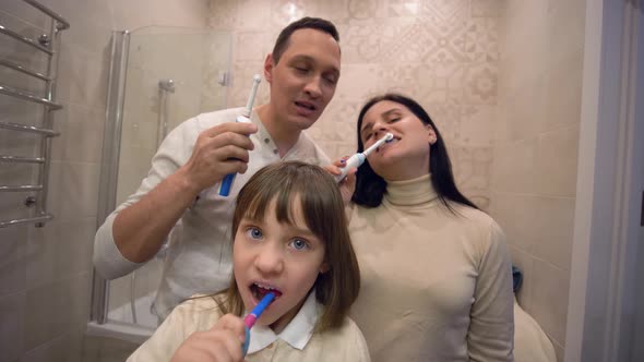 Morning Grooming, Healthy Little Kid Girl with Family with Toothbrush Brush Teeth in Front of Mirror