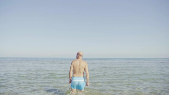 Rear view of senior man walking into water