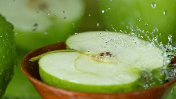 Super Slow Motion Shot of Water Splashing on Fresh Cutted Green Apple at 1000Fps