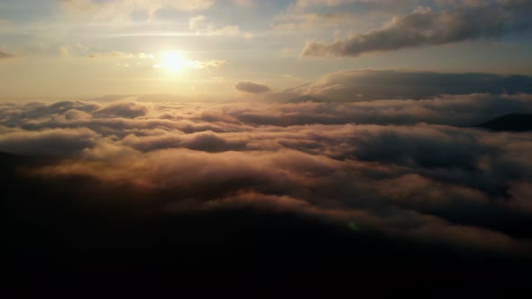 Aerial view: Flying Over Clouds on Sun Rise in Mountains.