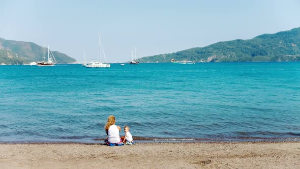 Young Mother and Son Relaxing and Play Ind Sand Games on Beach at Summer Season