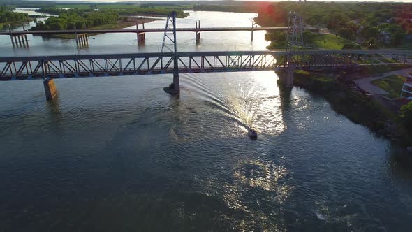 Boat going under a bridge at sunset in 4K