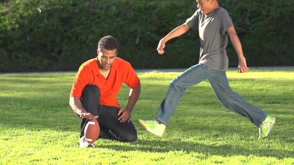 A father teaching his sons how to play American football.