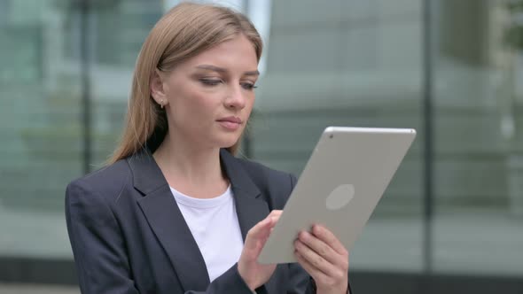 Attractive Young Businesswoman Using Tablet While Walking on the Street