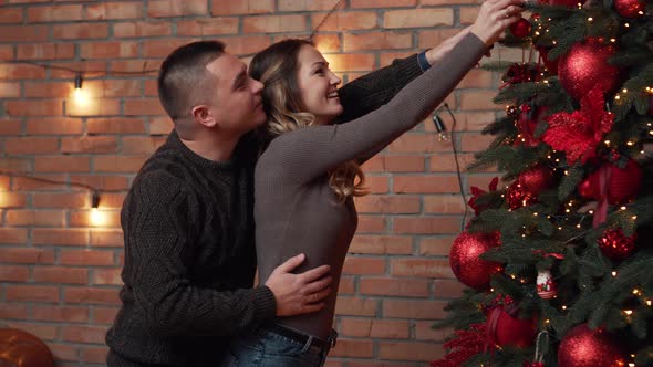 Young Couple Decorating Christmas Tree Together at Home