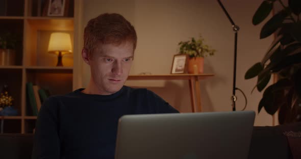 Crop View of Handsome Red Haired Man Using Laptop While Sitting on Sofa at Home