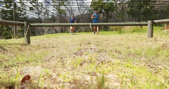 Fit man and woman crawling under the net during obstacle course