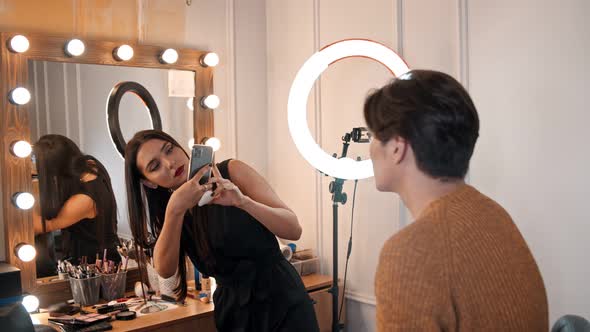 Makeup Studio - Woman Artist Taking Photos on Her Phone of Her Male Model with Makeup