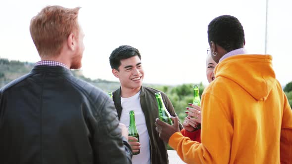 Multiethnic Young Fiends Drinking Beer Talking and Laughing in a Rooftop