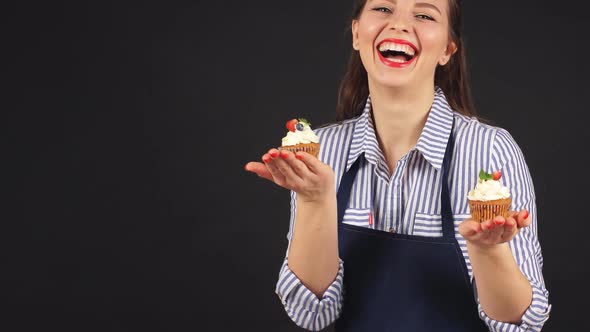 Young Woman Pastry Chef with Cupcakes in Hand Smiling at Camera