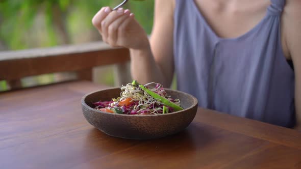 A Young Woman in a Tropical Cafe Eat Healthy Vegetarian Salad. Vegan Food Concept. Slowmotion Shot