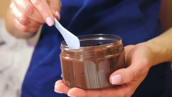 Beautician Takes Chocolate Cream for Beauty Procedure From Jar with Spatula