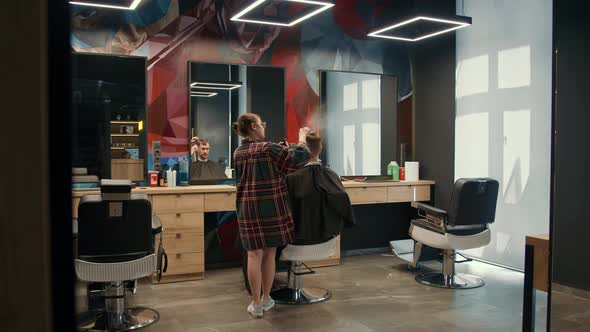 Barbershop: a woman barber cuts a client's man's hair