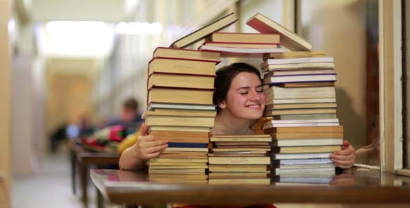Student Gazing Through House-Shaped Stack Of Books