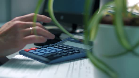 Man office worker calculates the company's profits and losses using a calculator. Close-up.