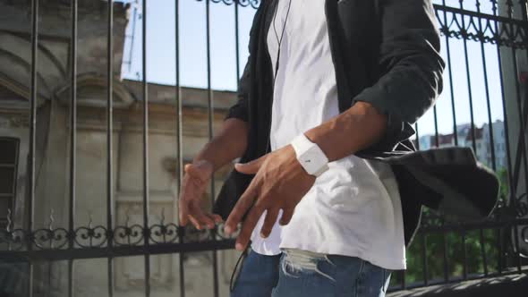 Young Stylish Hipster Black Man in White Headphones and Sun Glasses Walking and Dancing Outdoor in