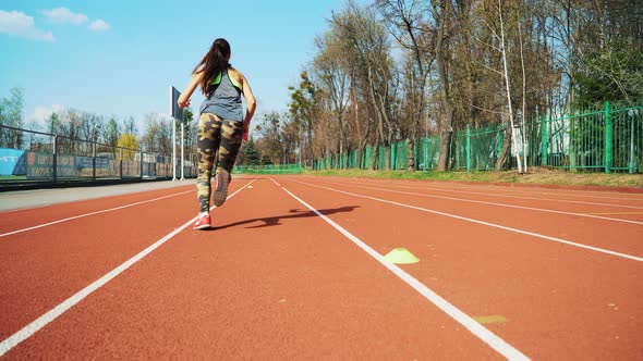 Young woman go in for sport run at the stadium track in the morning