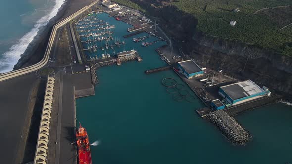 Tazacorte harbor on La Palma island coast and volcanic cliffs in background. Aerial forward tilt up