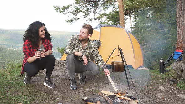 Young Couple of Tourists Makes a Fire for Cooking.