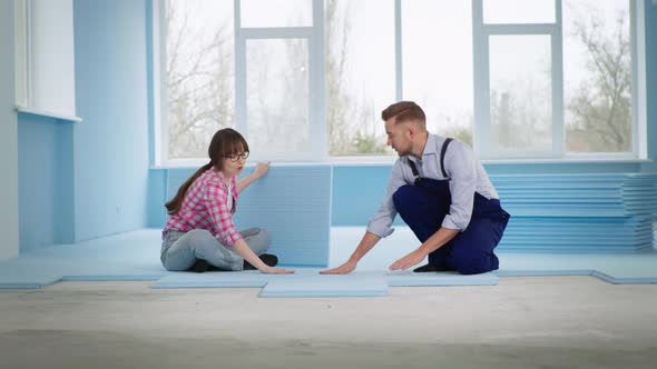 Master Man Together with Smiling Woman Insulate Floor with Expanded Polystyrene for Laying Laminate