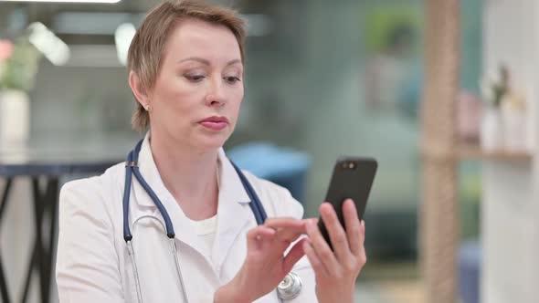Focused Middle Aged Female Doctor Using Smartphone