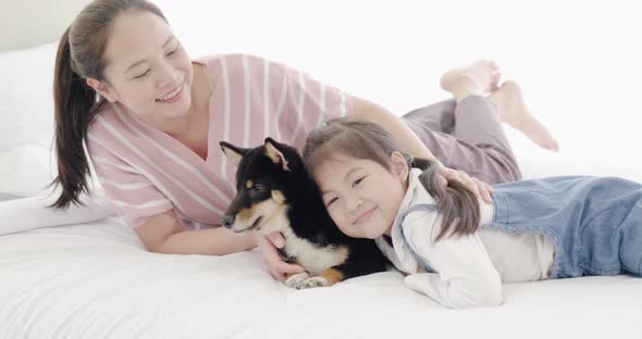 Mother and daughter playing with black dog on bed (11)