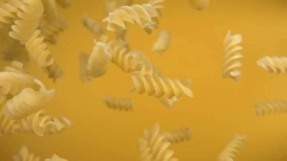 Dry Pasta Fusili Falling Diagonally on a Yellow Background