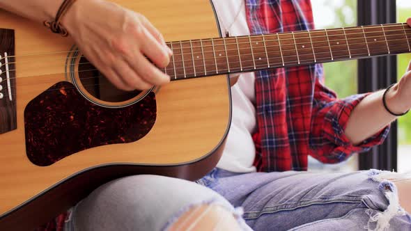 Young Man Playing Guitar Sitting on Windowsill