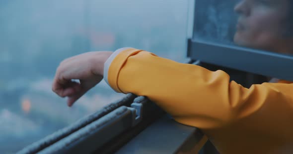 Young man moving his fingers while reaching out of window with foggy view
