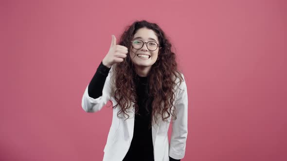 Happy Young Woman with Curly Hair with Her Hands Shows Her Thumb Up As a Sign Recommending Smiling