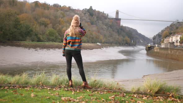 woman standing by the riverside of Bristol looking at the suspension bridge