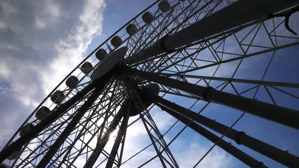 Ferris Wheel and Sun in Sky with Clouds