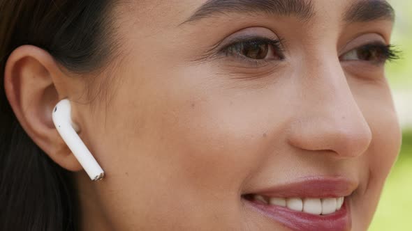 Woman Wearing Earbuds Listening To Music Looking Aside Outdoors Closeup