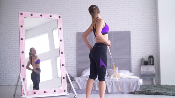 Sporty Woman with Measuring Tape Looking at Mirror