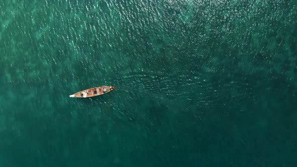 Aerial flight above wedding couple lyes down on long boat among bright turquoise sea