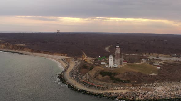 An aerial view of the Montauk lighthouse during a cloudy sunset. The drone camera truck left slowly,