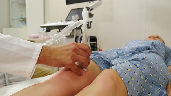 Orthopedic Doctor Makes Ultrasound Examination of Patient Knee Joint