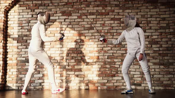 Two Fencers Are Practicing Against a Brick Wall Indoors