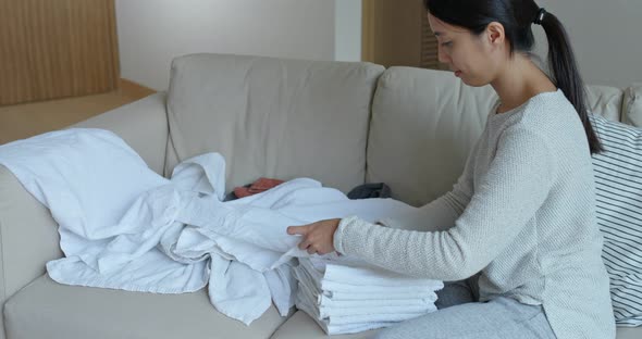 Woman doing housework, fold white towel at home