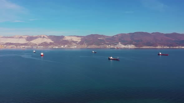 Vessels Drift on Calm Blue Ocean Surface Against Hilly Coast