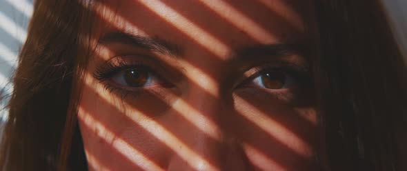 Closeup portrait of a woman through shadow os shutters