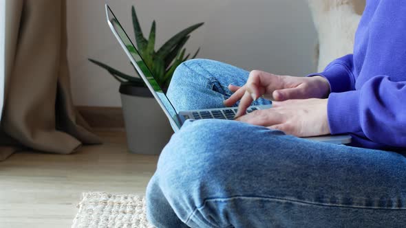 Young woman sitting on the floor working on her laptop.