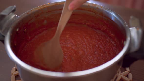 Unrecognizable cook pouring blended tomatoes in saucepan