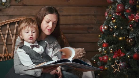 Mother and Child Reading a Book Under Christmas Tree