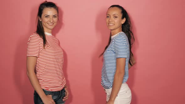 Two young beautiful smiling hipster girls in summer clothes posing in studio