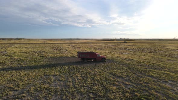 Aerial drone clip of a red isolated truck parked in the middle of a dry plain in a countryside lands