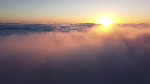 Orange sun on the horizon and immersion in the thick morning fog, flying in the clouds on a drone